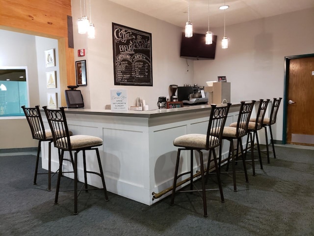 bar featuring baseboards, a bar, carpet flooring, and pendant lighting