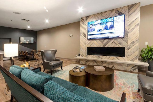 living area with recessed lighting, visible vents, wood finished floors, a tile fireplace, and baseboards