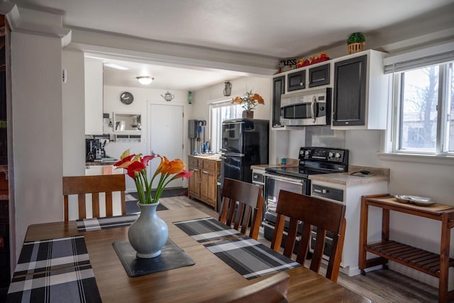 kitchen with stainless steel microwave, range with electric cooktop, light countertops, and light wood-style floors