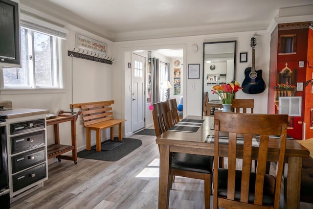 dining room featuring visible vents, baseboards, light wood-style floors, and ornamental molding