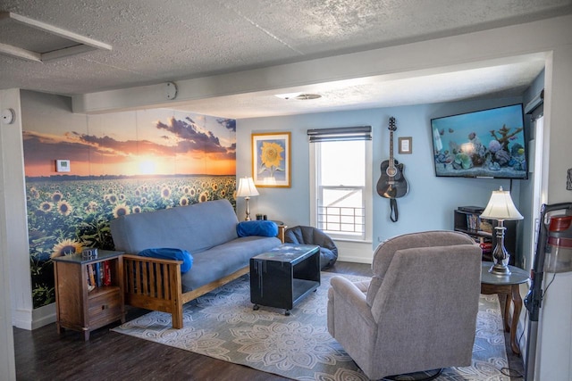 living room featuring attic access, a textured ceiling, baseboards, and wood finished floors