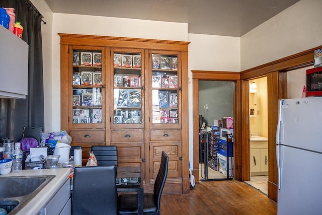 kitchen with a sink, light countertops, wood finished floors, and freestanding refrigerator