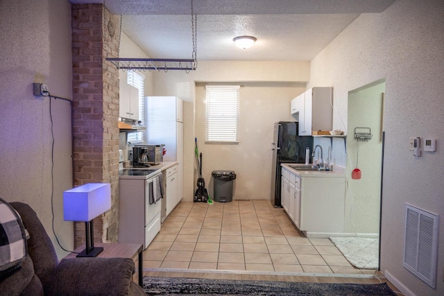 kitchen featuring light tile patterned floors, a sink, visible vents, white cabinets, and white range with electric stovetop