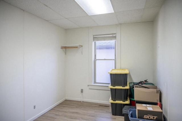 interior space featuring a drop ceiling, visible vents, baseboards, and wood finished floors