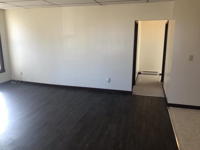 unfurnished room featuring a paneled ceiling, baseboards, a baseboard heating unit, and wood finished floors