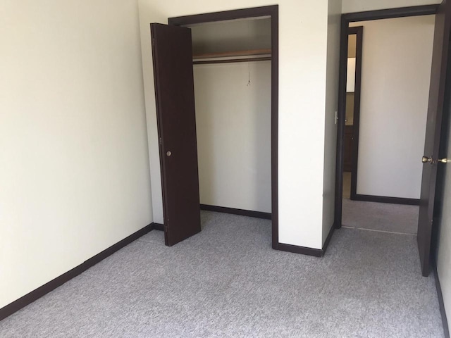 unfurnished bedroom with a closet, carpet, and baseboards