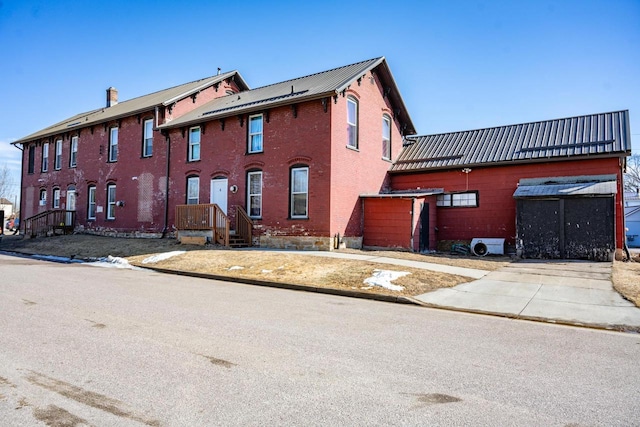 view of front of home with metal roof and brick siding