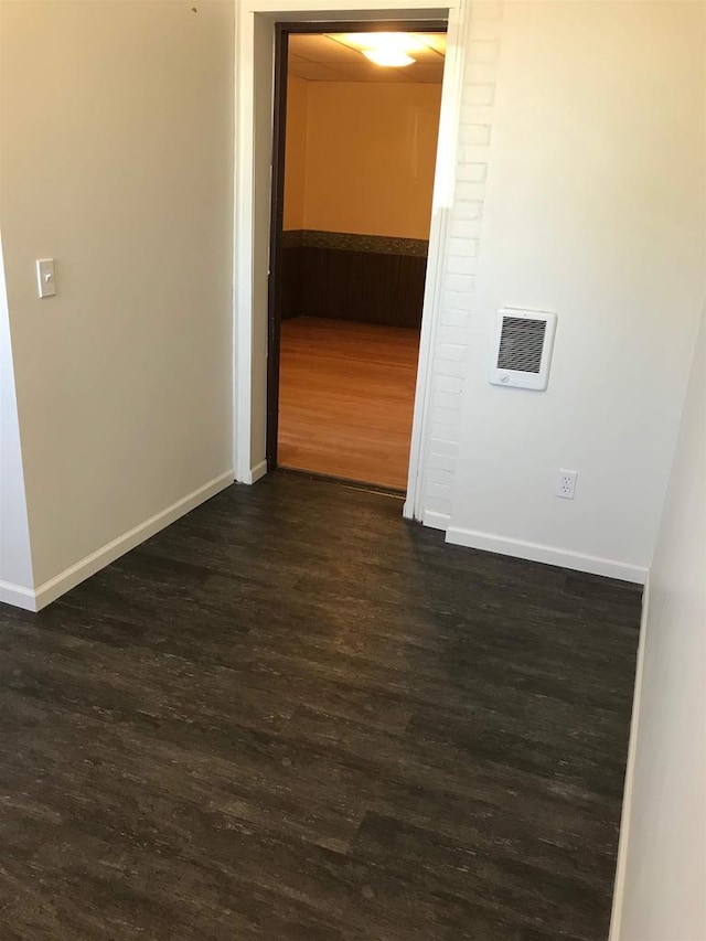 spare room featuring dark wood-style flooring and baseboards