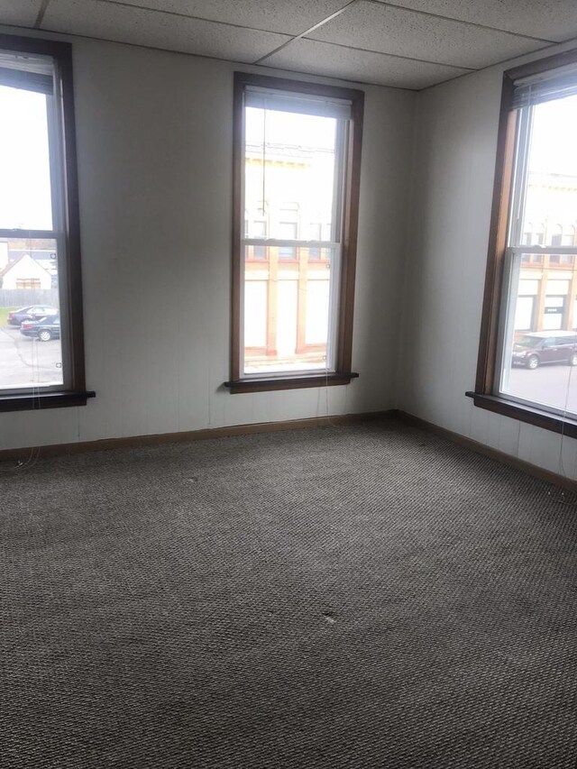 carpeted spare room with a paneled ceiling and baseboards