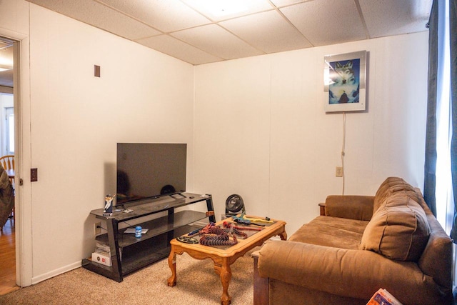 living area featuring a paneled ceiling and light colored carpet