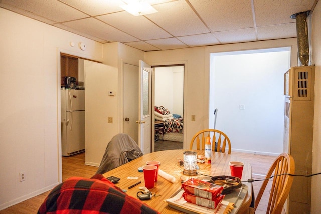 dining area featuring a drop ceiling, wood finished floors, and baseboards