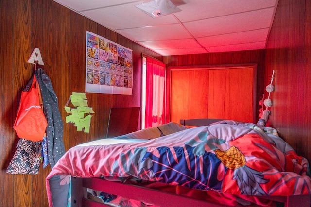 bedroom with a drop ceiling and wooden walls