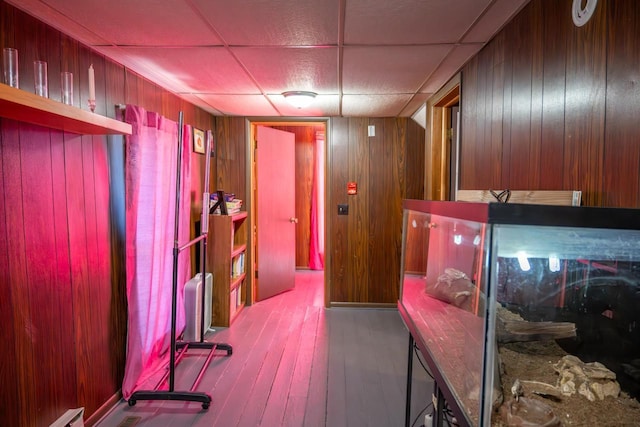 interior space with wood finished floors, a paneled ceiling, and wooden walls