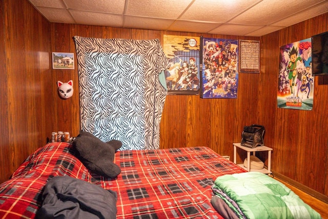bedroom featuring a paneled ceiling and wooden walls