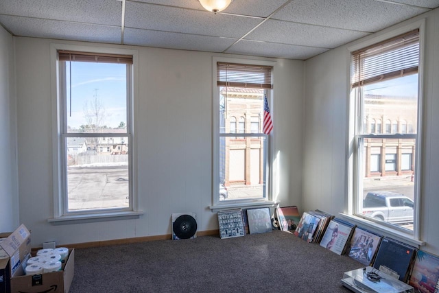 carpeted empty room with a paneled ceiling and baseboards
