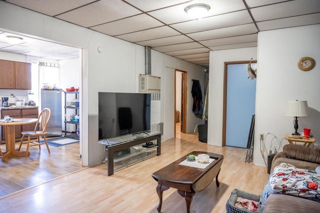 living area featuring a drop ceiling and light wood-style flooring