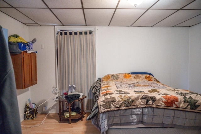 bedroom with a drop ceiling and wood finished floors