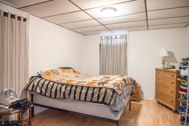 bedroom featuring a drop ceiling and wood finished floors