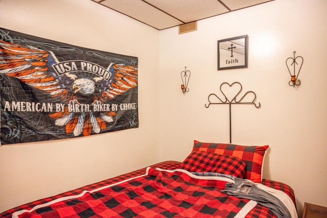 bedroom with a drop ceiling and visible vents