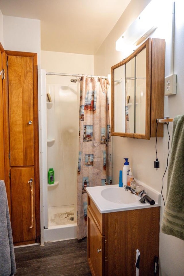 full bathroom with a shower stall, wood finished floors, and vanity