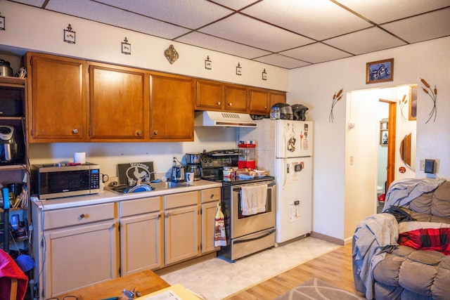 kitchen featuring a drop ceiling, under cabinet range hood, stainless steel appliances, a sink, and light countertops