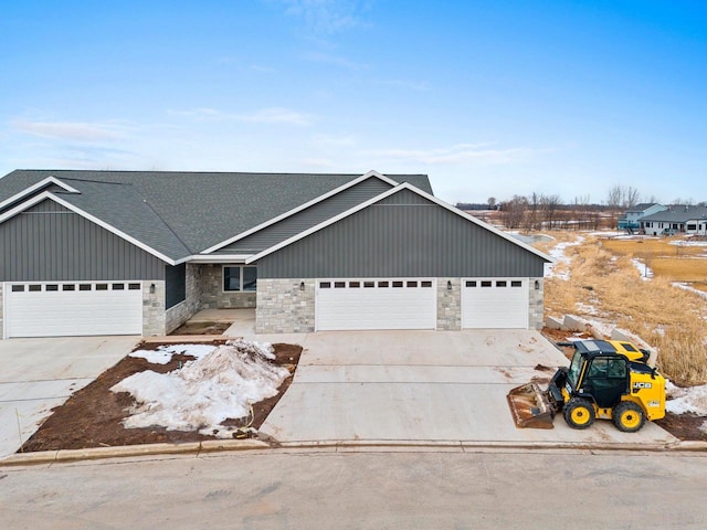 view of front facade featuring an attached garage, stone siding, concrete driveway, and roof with shingles