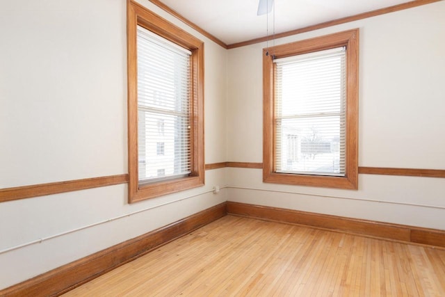 unfurnished room featuring ornamental molding, light wood-type flooring, baseboards, and a ceiling fan