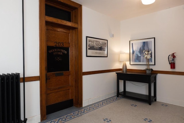 corridor featuring radiator heating unit, carpet, and baseboards