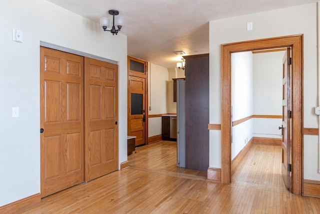 interior space featuring baseboards, light wood finished floors, and a notable chandelier