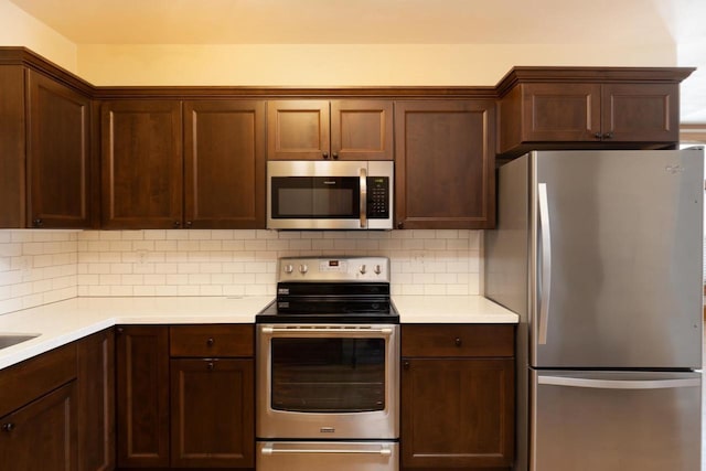 kitchen with dark brown cabinetry, tasteful backsplash, stainless steel appliances, and light countertops