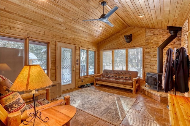 interior space with lofted ceiling, a wood stove, wooden ceiling, and wood walls