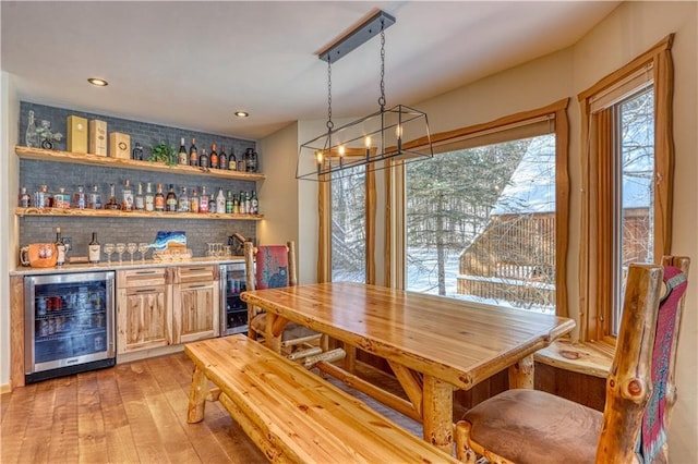 dining area with light wood-style floors, recessed lighting, beverage cooler, and a dry bar