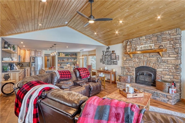 living area with light wood-type flooring, wooden ceiling, vaulted ceiling, and a stone fireplace