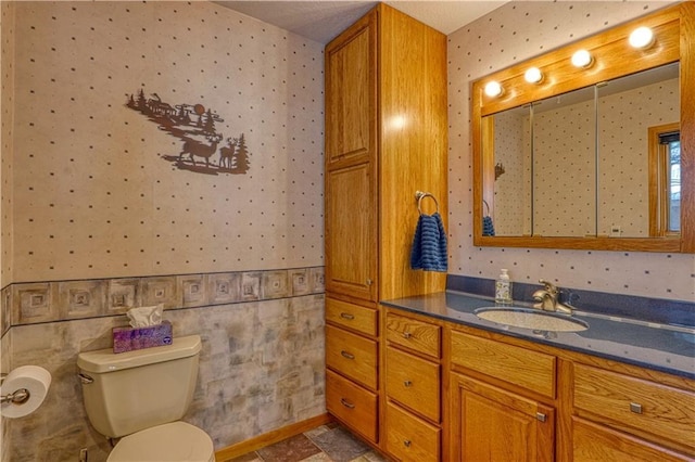 bathroom featuring vanity, toilet, and wallpapered walls