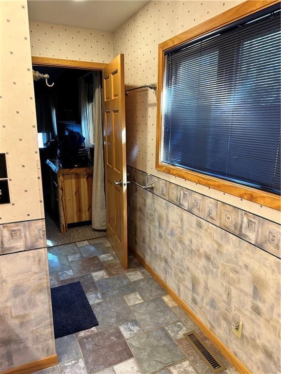 kitchen featuring stone tile flooring, visible vents, and wallpapered walls