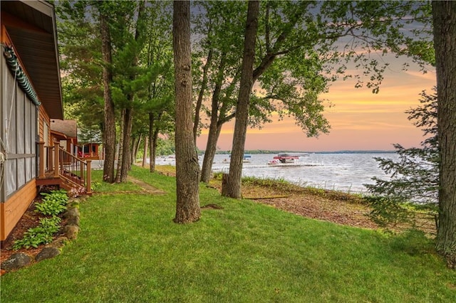 yard at dusk featuring a water view