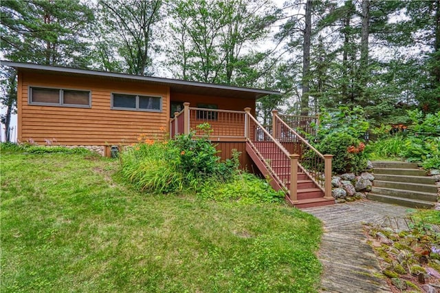 exterior space featuring a lawn, stairway, and a wooden deck