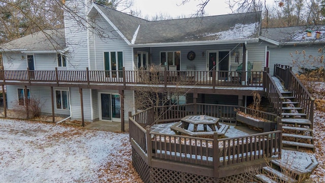 rear view of house featuring a chimney, a deck, and roof with shingles