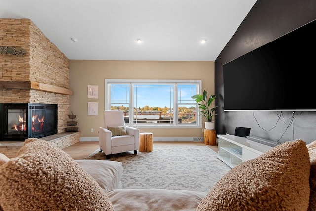 living room featuring a fireplace, vaulted ceiling, baseboards, and wood finished floors