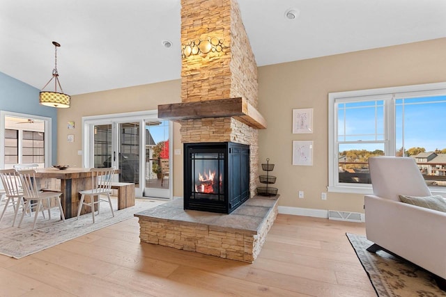 living room with wood-type flooring, a fireplace, visible vents, and baseboards