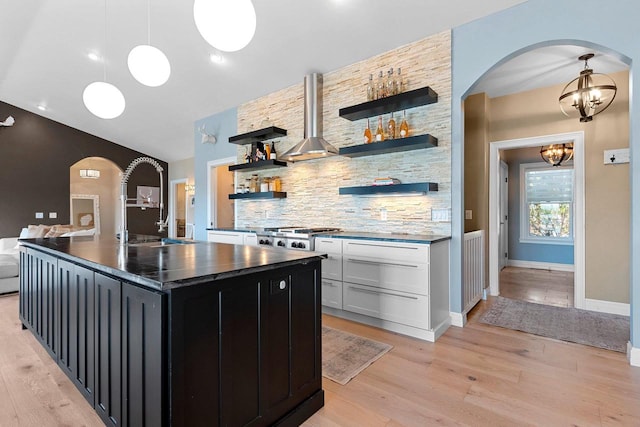 kitchen with arched walkways, open shelves, dark countertops, backsplash, and dark cabinetry