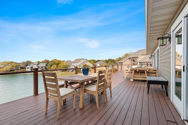 wooden terrace featuring outdoor dining space, a water view, and a residential view