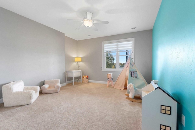 recreation room with carpet floors, a ceiling fan, and baseboards