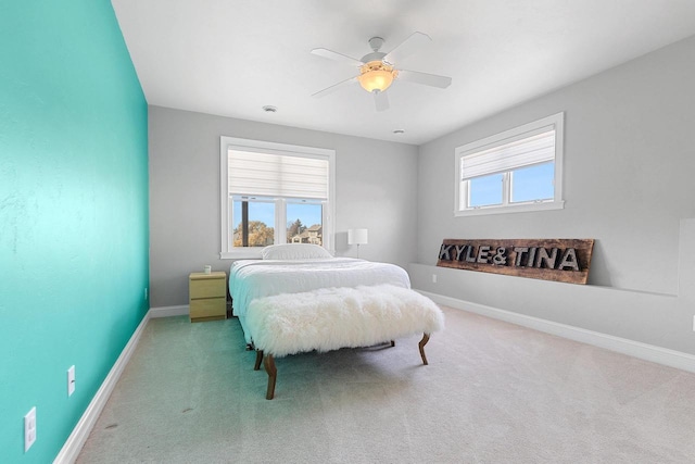 carpeted bedroom with multiple windows, a ceiling fan, and baseboards