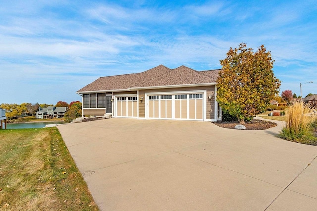 view of front facade with a front lawn, concrete driveway, a sunroom, and an attached garage