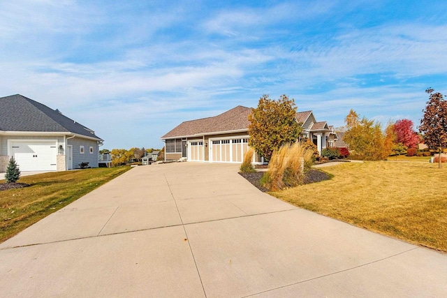 view of front of home featuring an attached garage, concrete driveway, and a front yard