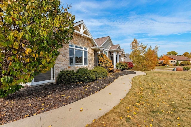 view of side of home with stone siding and a yard