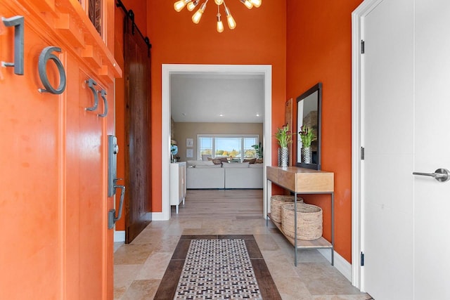 hallway featuring a barn door, baseboards, and a chandelier