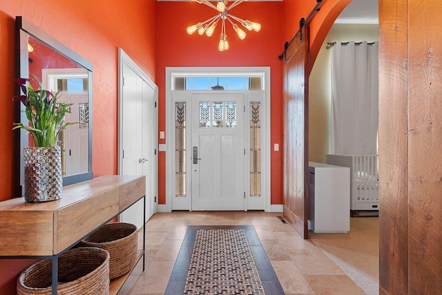 foyer with a barn door, arched walkways, and baseboards