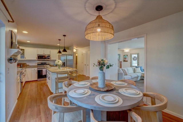 dining area featuring light wood-type flooring and baseboards